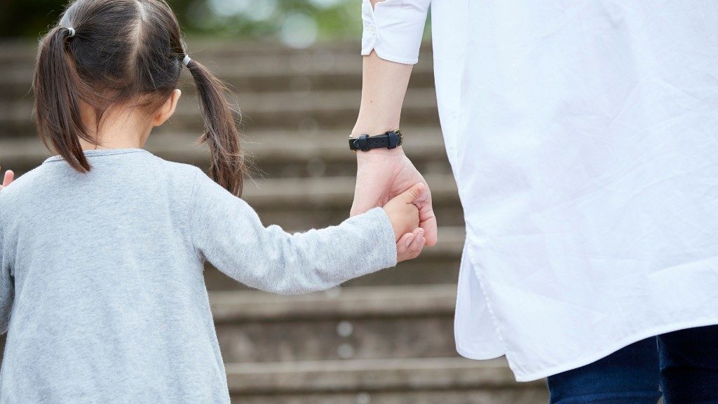 A parent and young girl holding hands as they walk up outdoor stone steps together