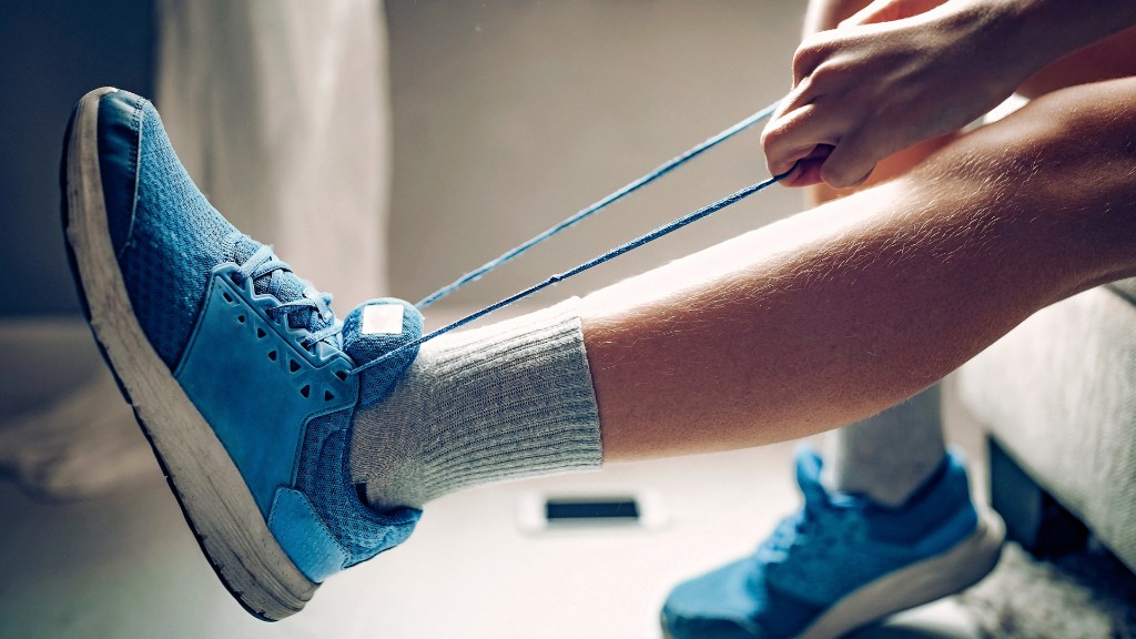 Close-up of hands tying the laces of a bright blue sneaker — a daily fine motor independence skill