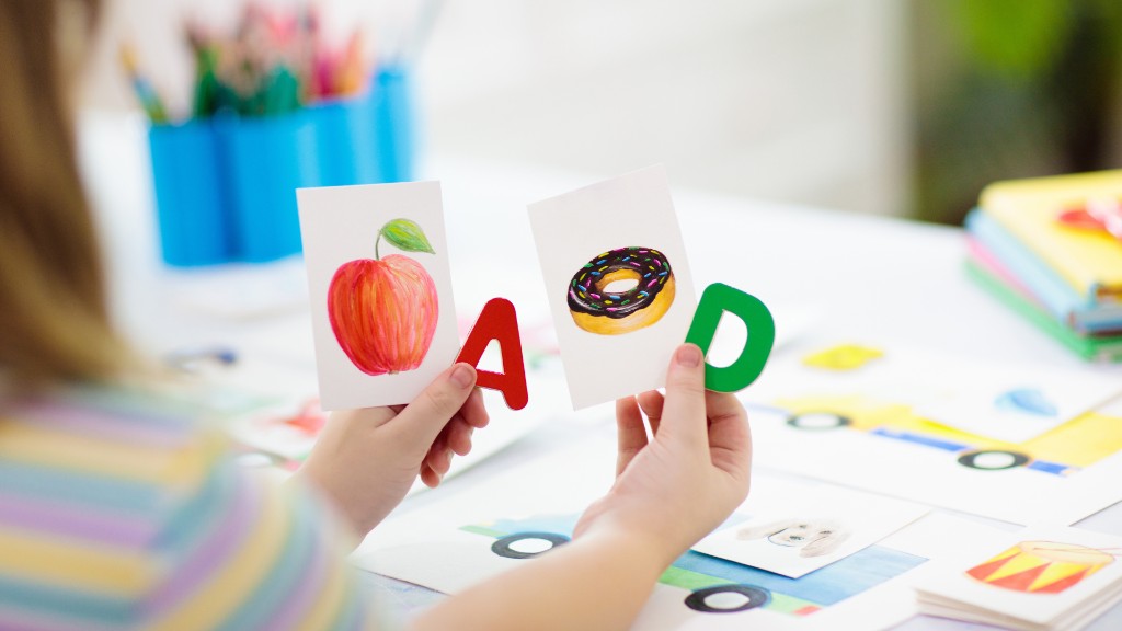 A child holding letter flashcards with pictures of an apple and a donut at a learning table