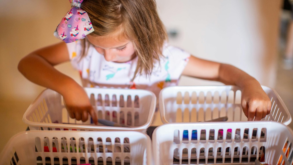 A young girl concentrating as she carefully arranges markers and supplies in white plastic baskets