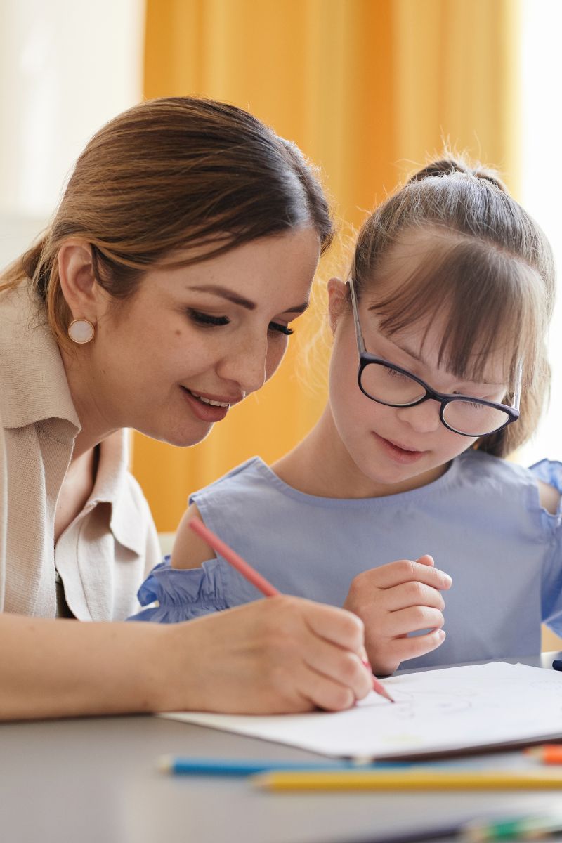 A parent and child drawing together at the kitchen table